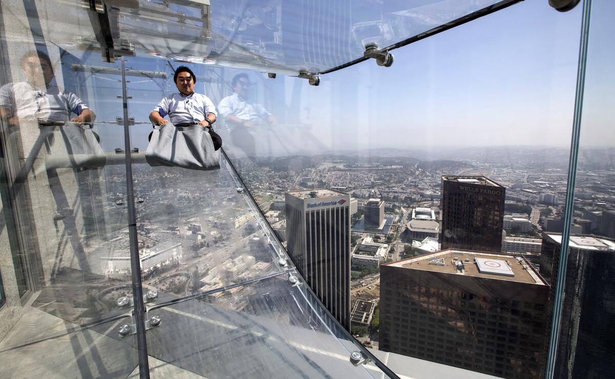 A man slips down a glass slide high above downtown Los Angeles