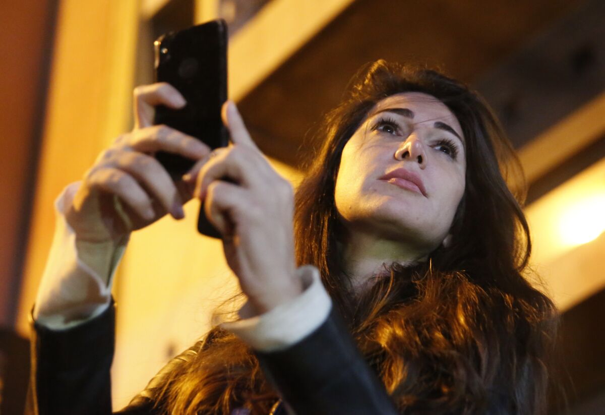 FILE - Lebanese Journalist Dima Sadek uses her cellphone to make a video of an anti-government protest, in Beirut, Lebanon, Dec. 4, 2019. The stabbing of author Salman Rushdie on Friday, Aug. 12, 20222 in western New York, has laid bear to divisions within Lebanon’s Shiite community of which some have expressed support for the act while others harshly criticized it leading to death threats against Sadek, a prominent journalist. The assailant, 24-year-old Hadi Matar, is a dual Lebanese-U.S. citizen, and his father lives in a village in Hezbollah-dominated southern Lebanon. (AP Photo/Hussein Malla, File)