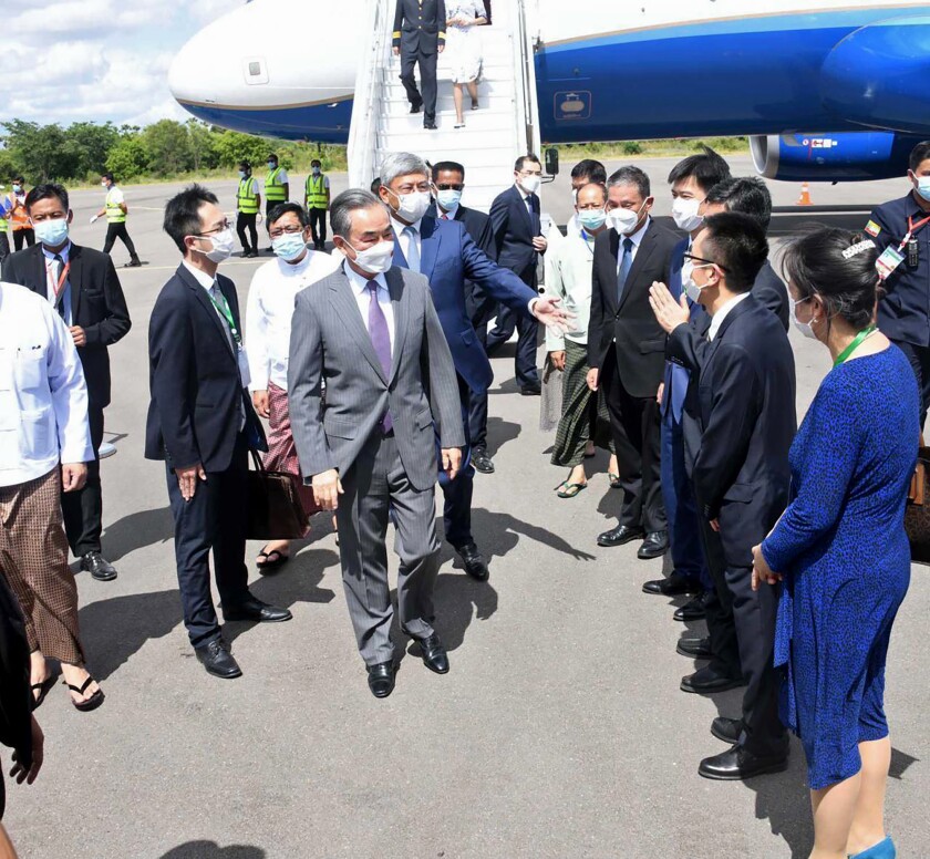 In this photo provided by the Myanmar Ministry of Information, Chinese Foreign Minister Wang Yi, center, is welcomed by Myanmar Foreign Ministry representatives and Chinese embassy officials upon his arrival at Nyaung Oo Airport in Bagan, Myanmar Saturday July 2, 2022. China's top diplomat has arrived on his first visit to Myanmar since the military seized power last year to attend a regional meeting. (Myanmar Ministry of Information via AP)