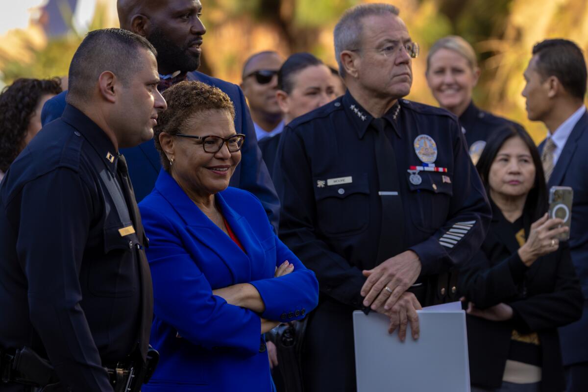 LAPD Capt. Christopher Zine, left, Mayor Karen Bass and former Chief Michel Moore among a crowd
