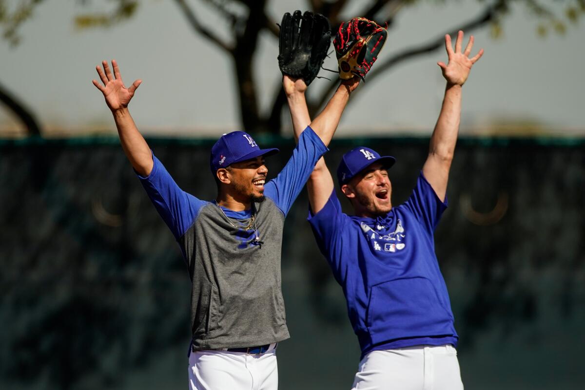 Dodgers teammates Mookie Betts, left, and Cody Bellinger cheer during a spring training practice session at Camelback Ranch on Feb. 19.