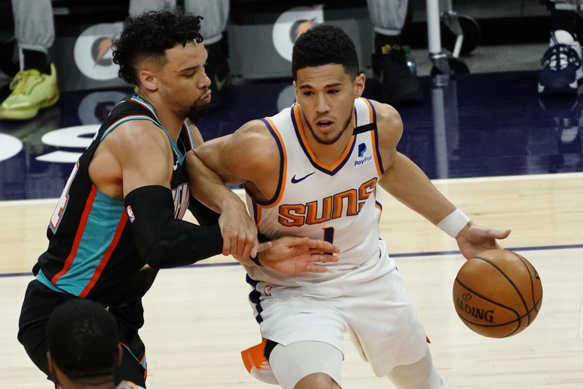 Phoenix Suns guard Devin Booker (1) is pressured by Memphis Grizzlies guard Dillon Brooks during the first half of an NBA basketball game Monday, March 15, 2021, in Phoenix. (AP Photo/Rick Scuteri)
