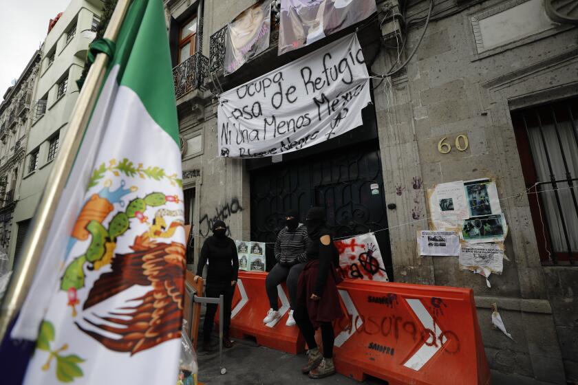 Masked demonstrators sit outside the National Human Rights Commission office which protesters have been occupying since last week in Mexico City, Tuesday, Sept. 8, 2020. Demanding justice for victims of femicide, gender violence, sexual assault, and forced disappearances, feminist activists and victims' relatives have taken over the commission's offices, saying they will continue the occupation until real progress is made in bringing perpetrators to justice. (AP Photo/Rebecca Blackwell)