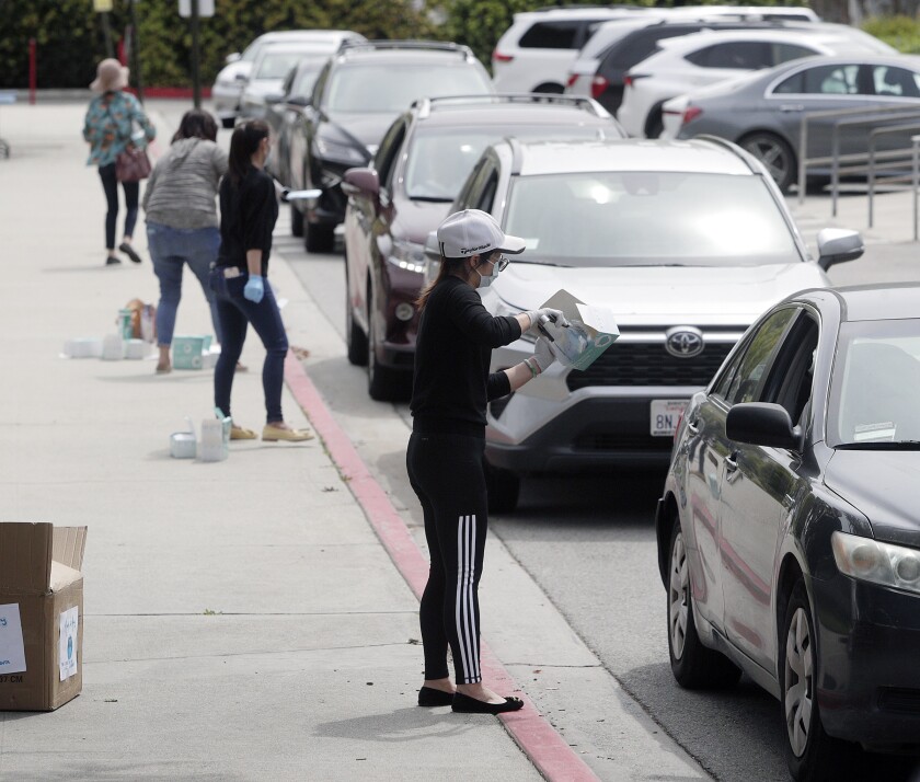 Members with the Chinese Club of La Cañada Flintridge and La Crescenta line up along the parking lot at the Foothill Chinese School on March 31 as they hand out face masks to senior citizens as part of the group's "Masks for Many" program to help protect the elderly amid the coronavirus pandemic.