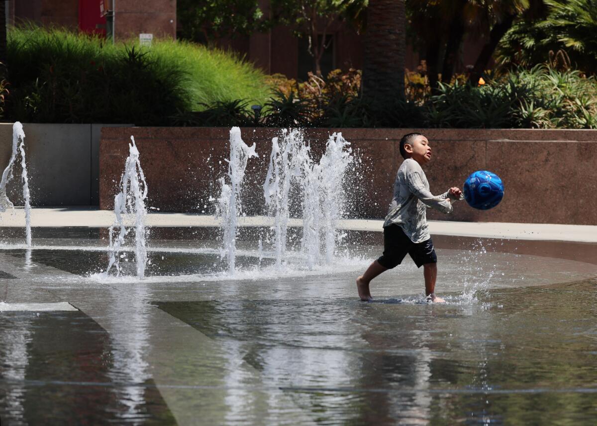 A child splashes as fountains bubble behind him.