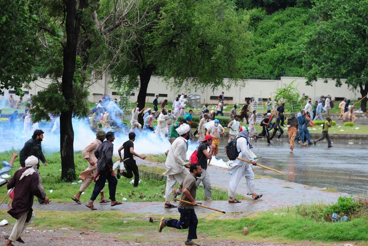 Pakistani protesters run toward police during clashes Monday near the prime minister's residence in Islamabad.