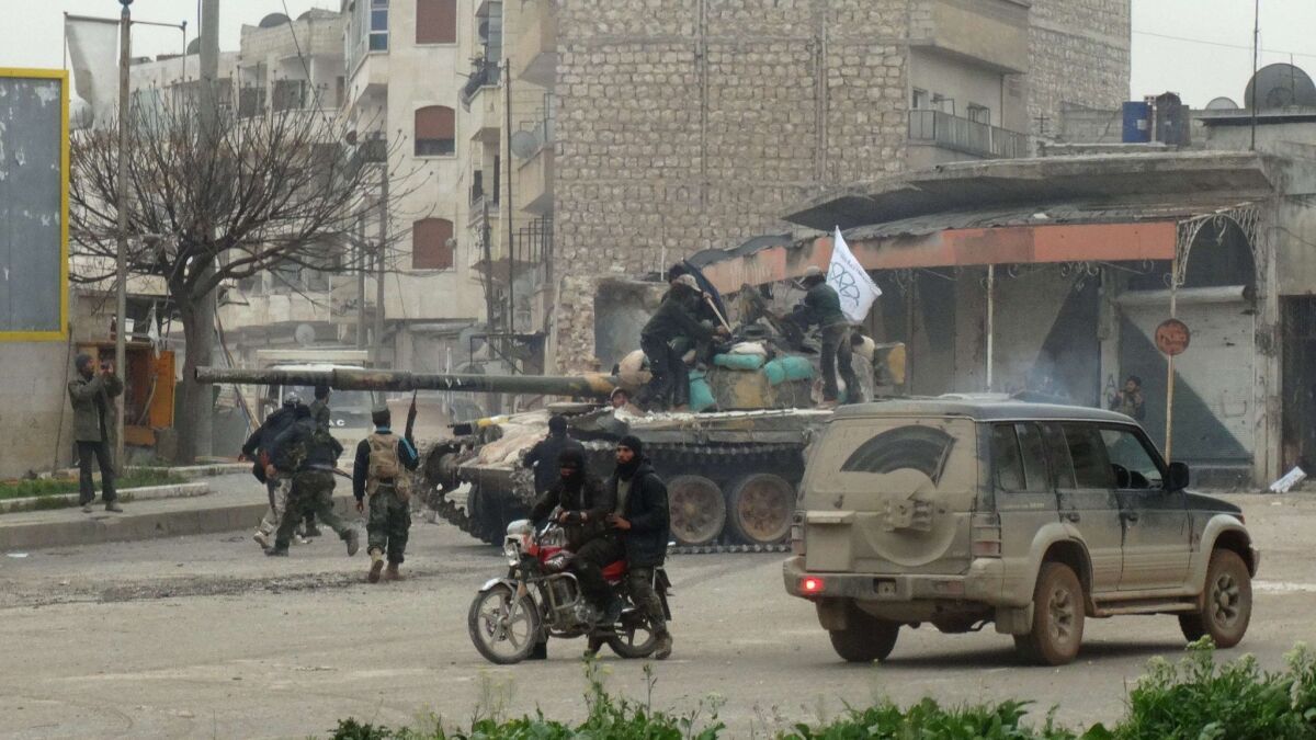 Fighters loyal to Al Nusra Front and its allies gather around a tank on a square in the northwestern Syrian city of Idlib on March 28, 2015.