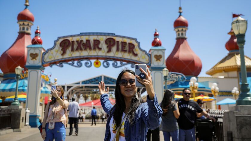 Visitors at California Adventure Park stop to shoot videos and take selfies at Pixar Pier. Many of those videos and pictures will appear on social media outlets.