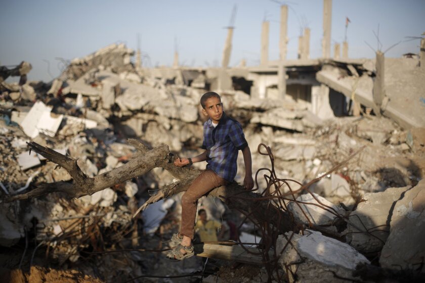 A Palestinian sits on March 31 amid the rubble of Gaza City buildings that were destroyed during the 50-day war between Israel and Hamas militants last summer.
