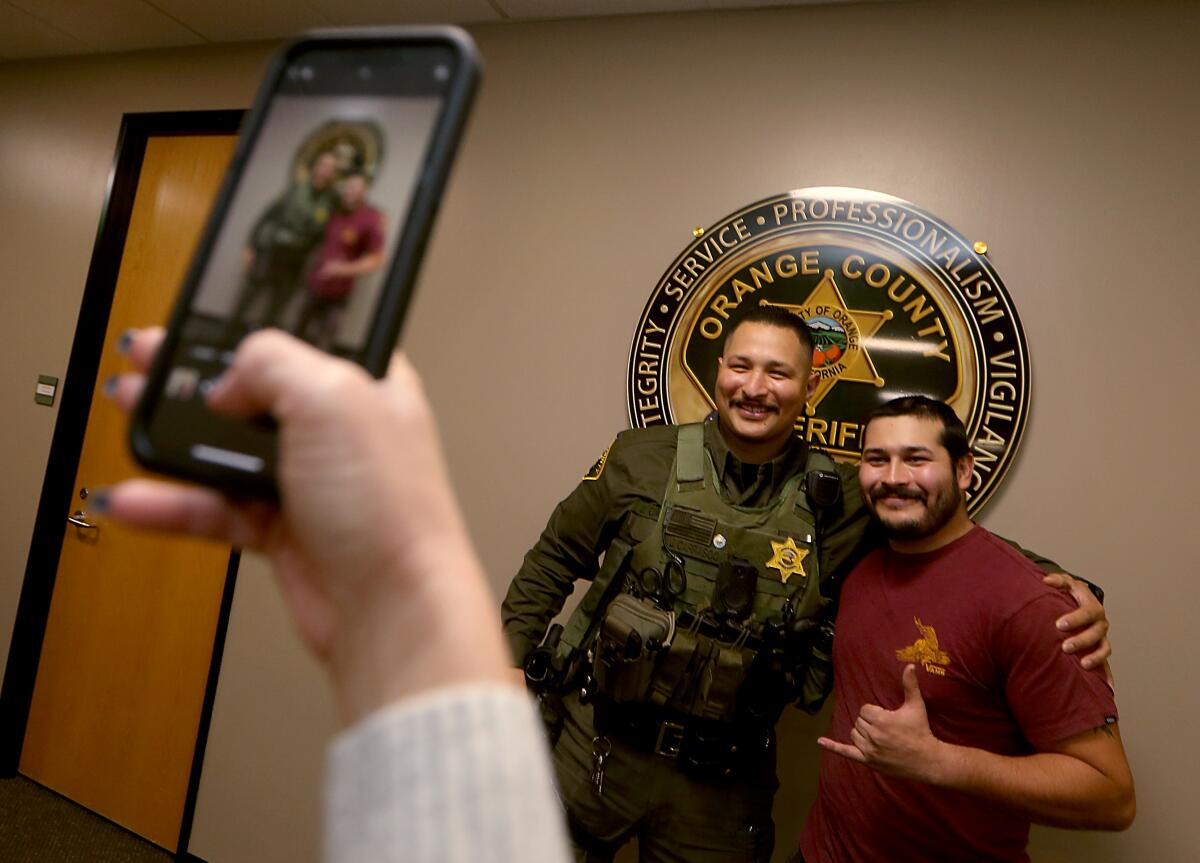 Two men pose for a photo in front of an Orange County Sheriff's Department seal.