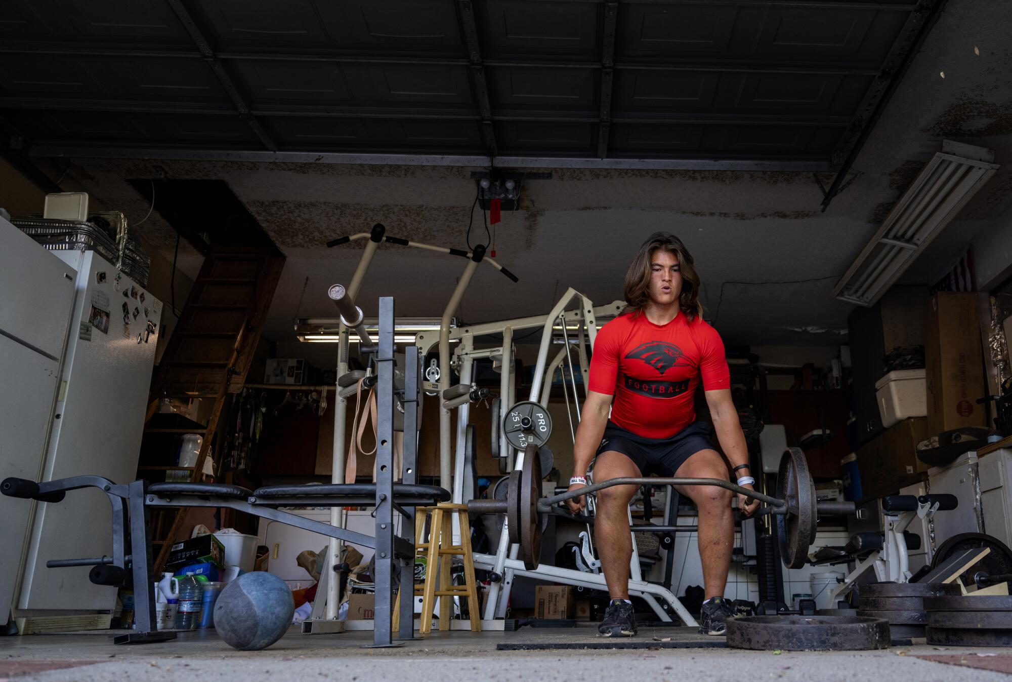 Quarterback Bear Bachmeier lifts weights in a makeshift weight room he has created in the garage of his family's home.