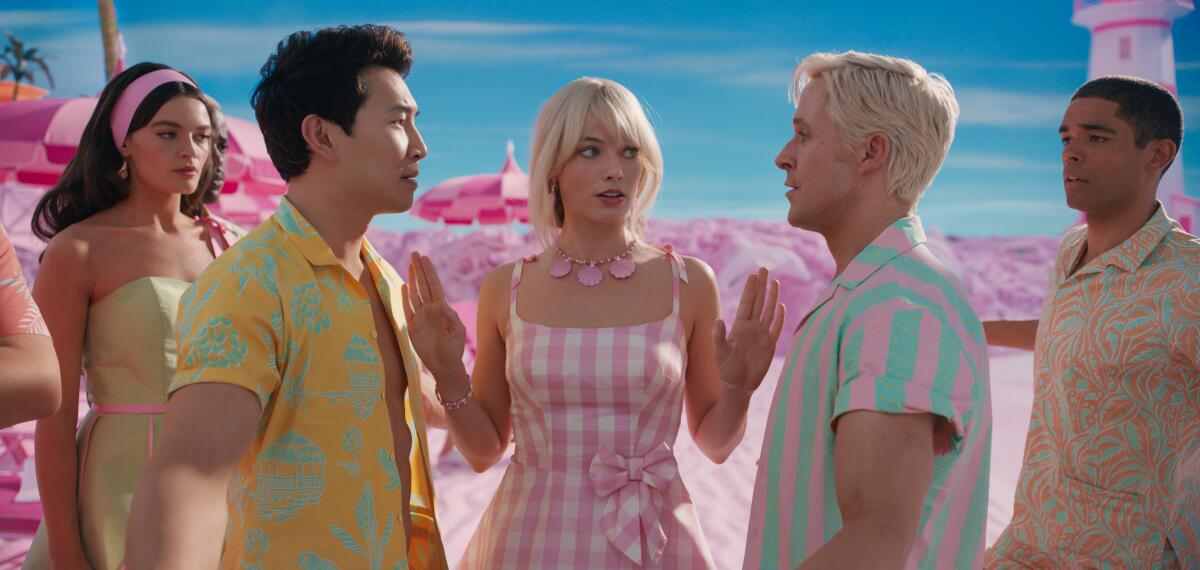 Barbie stands between two Kens staring each other down at a pink beach with another man and woman looking on
