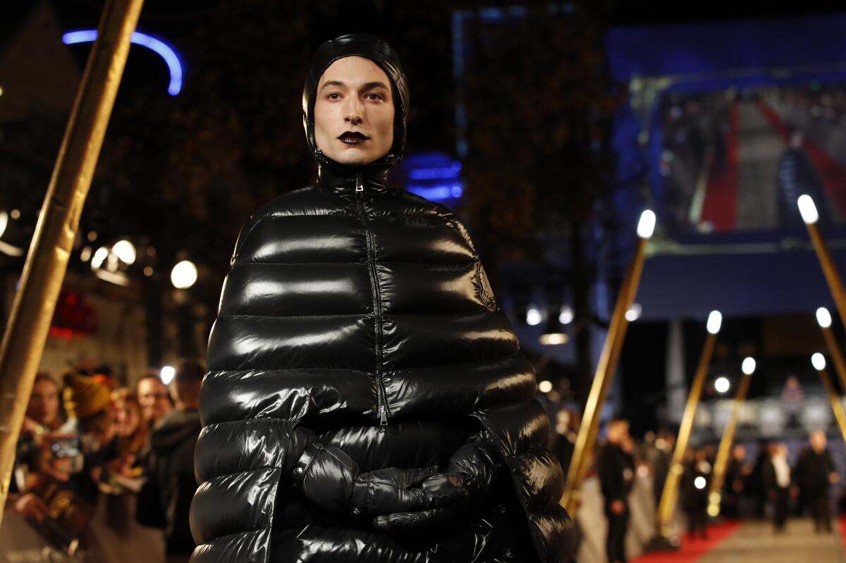 A person in a black quilted puffer that forms a triangle shape starting at their head
