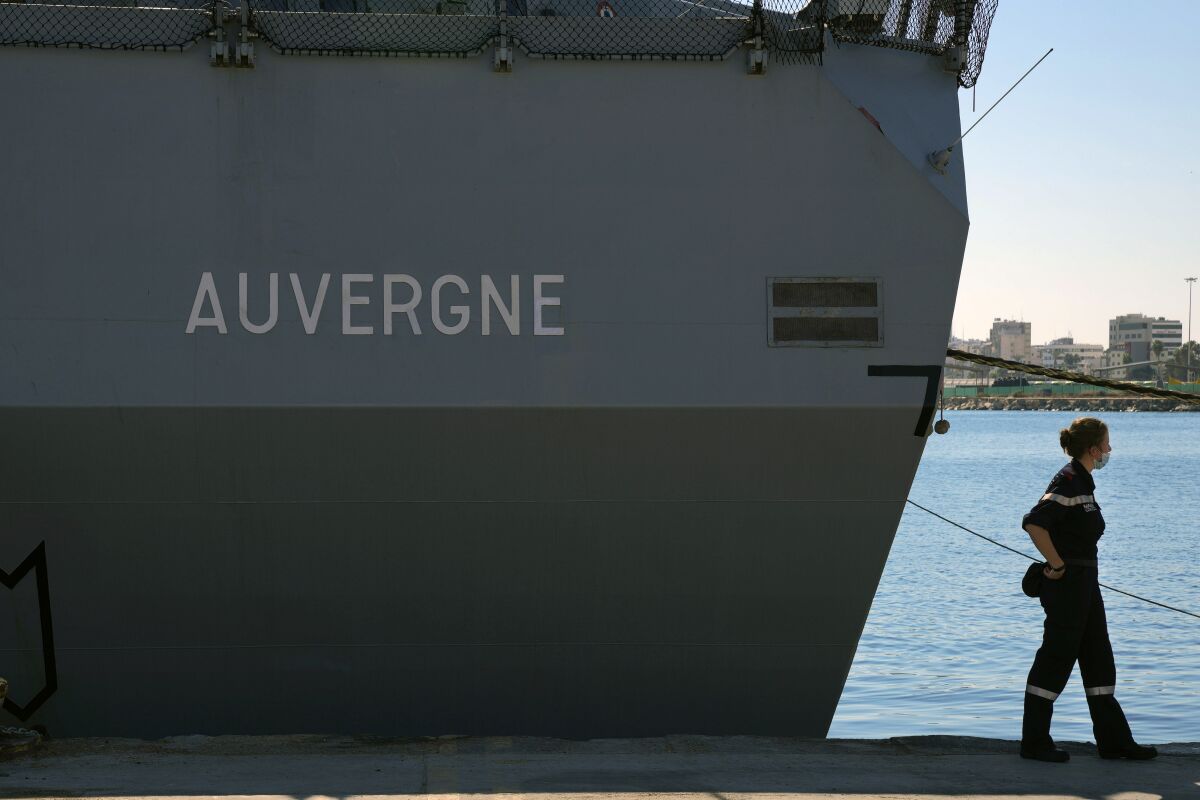 A sailor walks by the French frigate Auvergne during a port call at Cyprus' port of Larnaca on Monday, Nov. 8, 2021. The frigate's presence signals the French government's military muscle flexing as it tries to fill in a perceived regional power vacuum and to protect its interests including offshore hydrocarbon drilling rights that Cyprus granted to French energy company Total. (AP Photo/Petros Karadjias)
