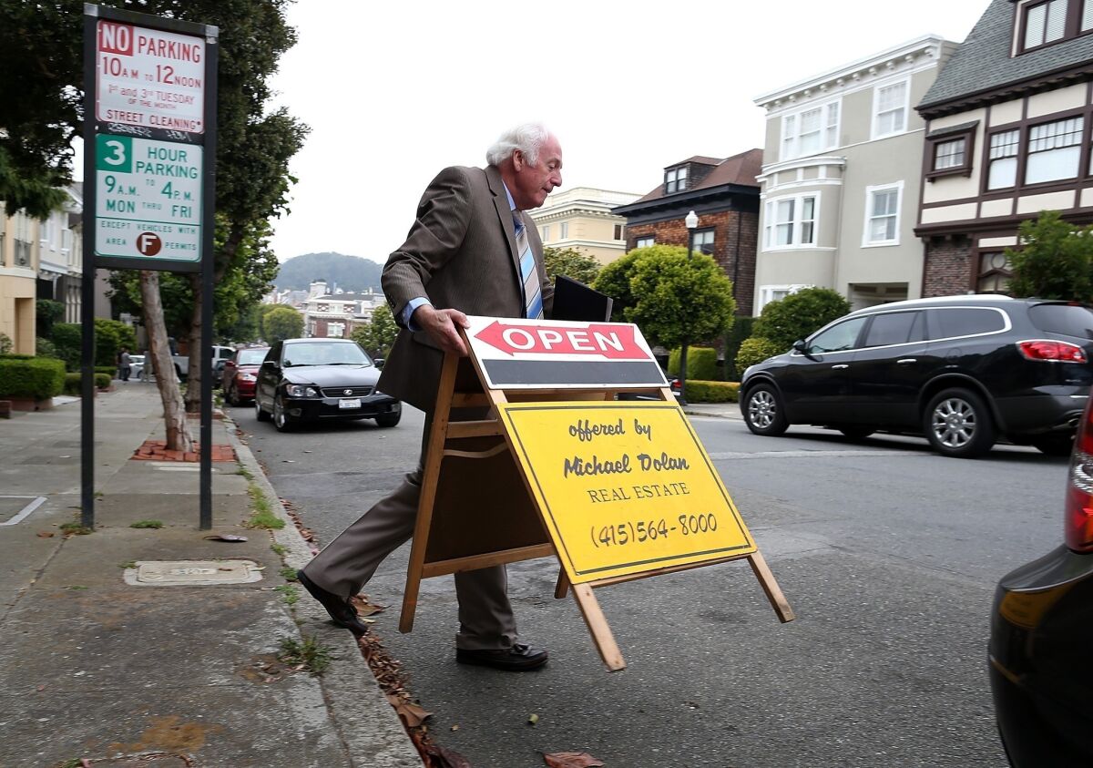 Demand for mortgages to purchase homes has increased as housing markets improve, although overall demand for home loans has declined as fewer homeowners find it worthwhile to refinance. Above, a real estate agent places an open-house sign in front of a home for sale in San Francisco last month.