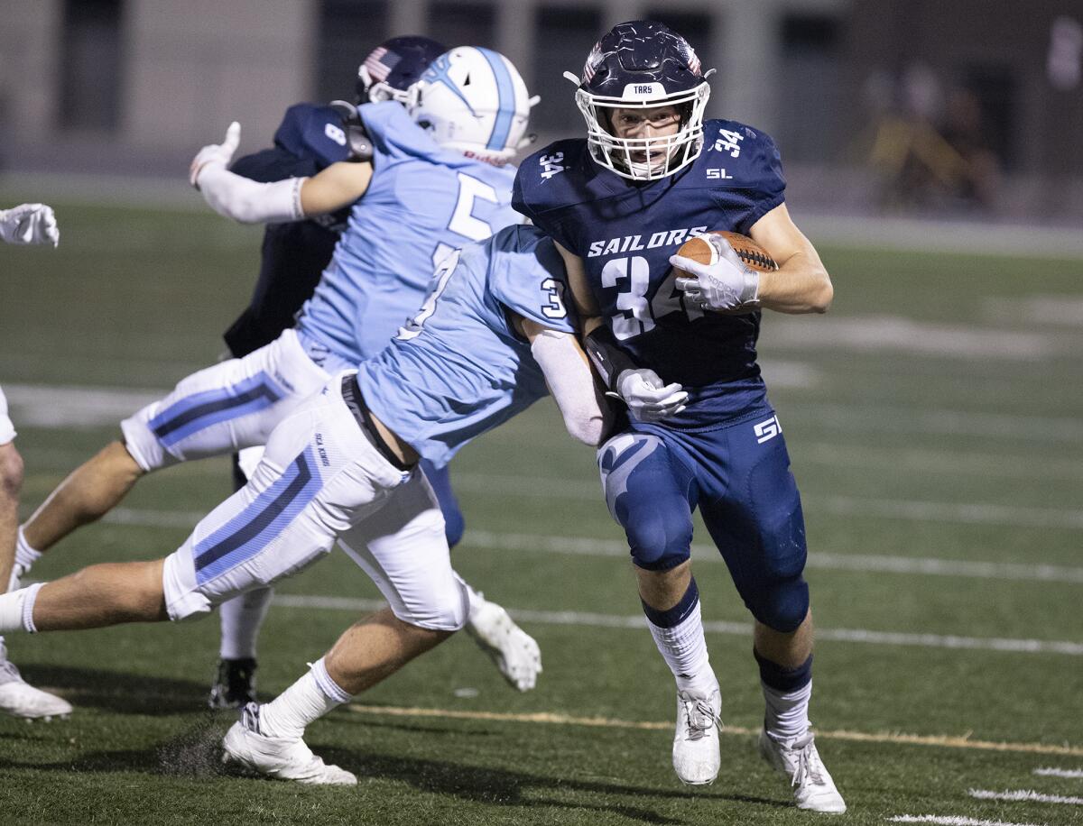 Newport Harbor's Payton Irving is tackled by Corona del Mar's Mason Kubichek during the Battle of the Bay football game.