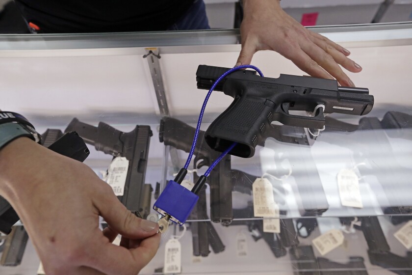 A, gun shop owner demonstrates how a gun lock works on a handgun
