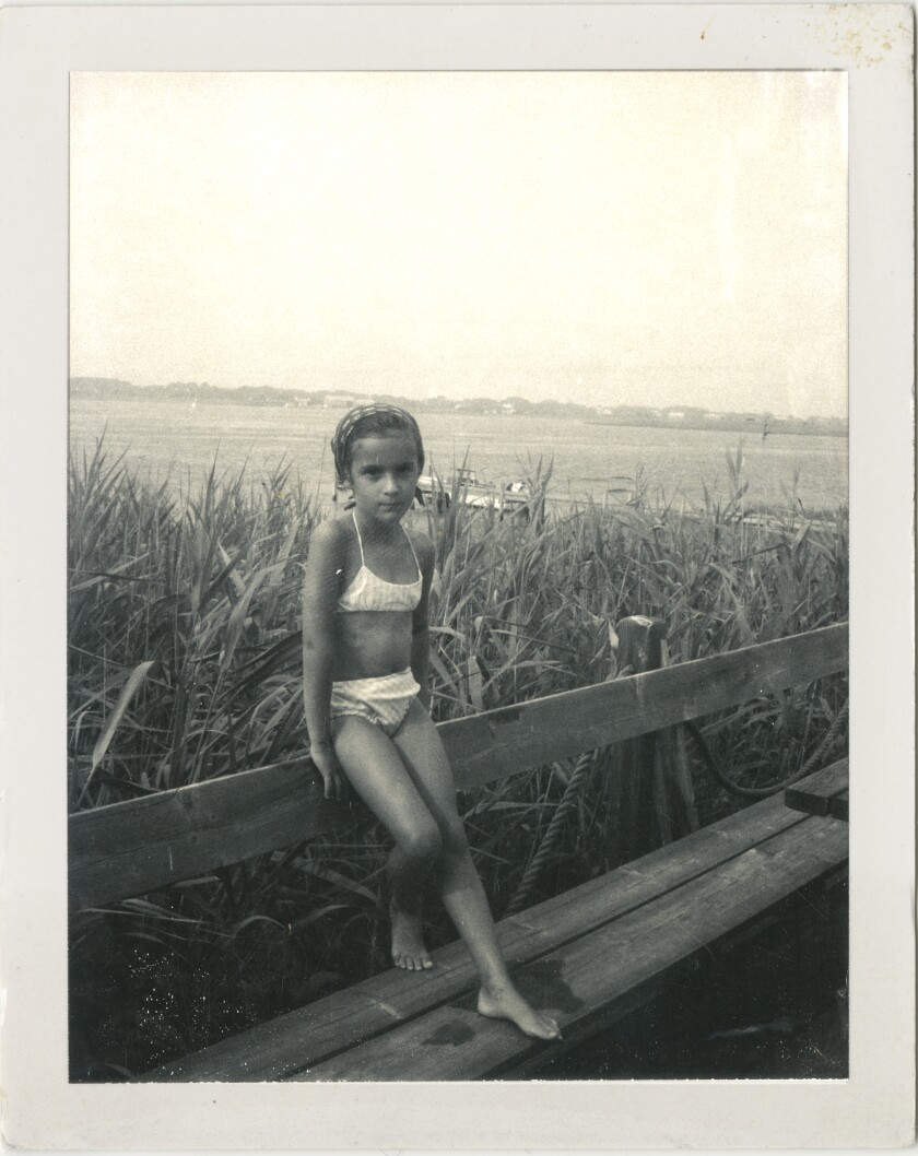 black-and-white photo of a child leaning against railing in front of an ocean