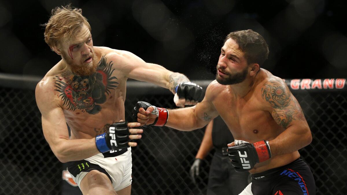 Conor McGregor, left, punches Chad Mendes during their interim UFC featherweight title bout at UFC 189 in Las Vegas on Saturday.