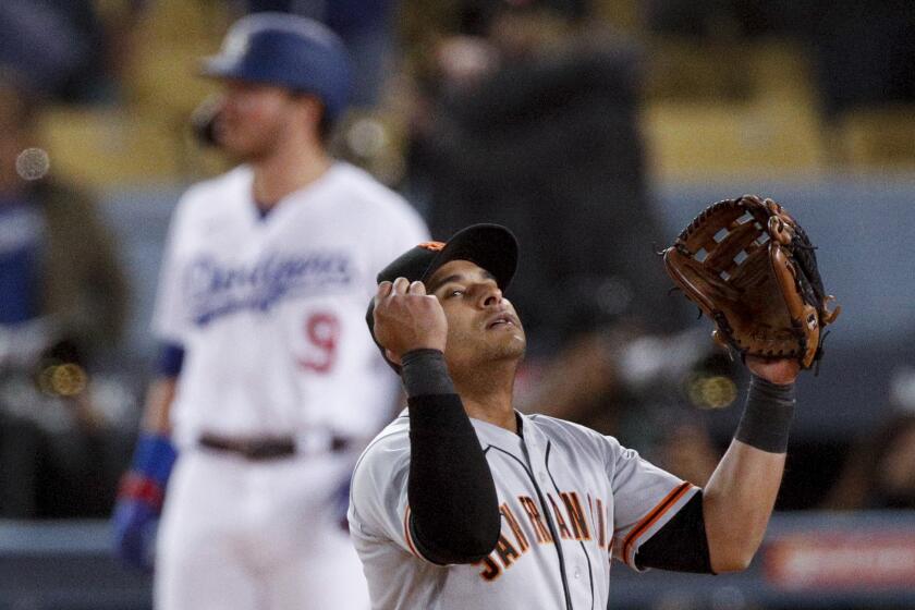 Giants second baseman Donovan Solano celebrates as Dodgers hitter Gavin Lux stands stunned.