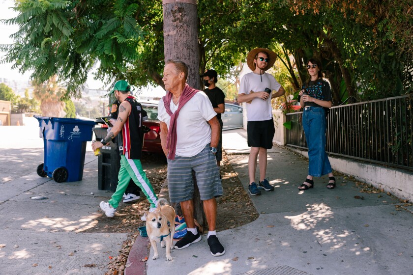 A man with a dog and others stand on a sidewalk