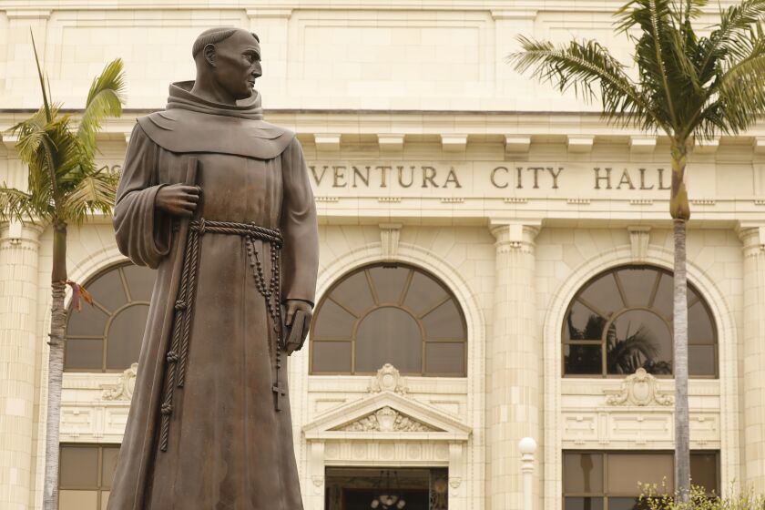 VENTURA, CA - JUNE 24: The bronze statue of Father Junipero Serra who founded nine Spanish missions in California including Mission San Buenaventura stands in front of Ventura City Hall. A joint statement was issued from local political, indigenous and Catholic leaders pledging to remove the monument, originally commissioned in the 1930s but replaced in 1989. "The time has come for the statue to be taken down and moved to a more appropriate nonpublic location," read the statement, issued by Ventura Mayor Matt LaVere. After a protest last weekend Ventura city spokeswoman Heather Sumagaysay said the city is making plans to host community discussions regarding the Serra statue and there is no timeline for its removal, she said. "It is our priority to be receptive to public concerns and provide an environment where all voices are heard and respected. A historic decision such as this will involve the voices of the Chumash tribe, the City Council and the residents of Ventura," Sumagaysay said in an emailed statement. "The city remains committed to collaborating with the community to determine next steps. We will inform the public of opportunities to participate and offer input at a future meeting." The move comes after a Father Serra statue was toppled last weekend on Olvera St. in downtown Los Angeles and people were considering changing the name of Ft Bragg, but voted the change down. Ventura City Hall on Wednesday, June 24, 2020 in Ventura, CA. (Al Seib / Los Angeles Times)