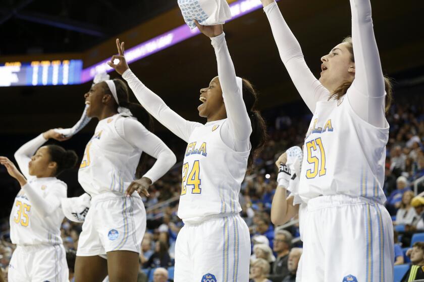 LOS ANGELES, CALIF. -- SUNDAY, DECEMBER 29, 2019: UCLA Bruins guard Camryn Brown (35), Michaela Onyenwere (21), Japreece Dean (24) and Eliana Sigal (51) cheer on teammates in a game against USC Trojans in the second half at Pauley Pavilion in Los Angeles, Calif., on Dec. 29, 2019. UCLA won 83-59. (Gary Coronado / Los Angeles Times)