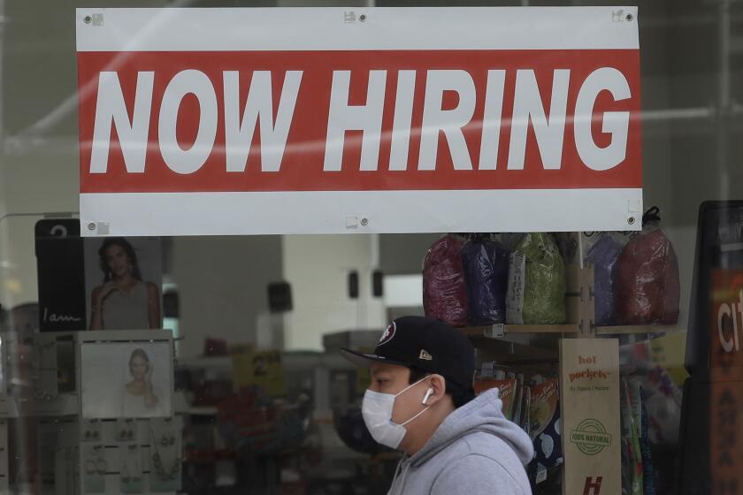 FILE - This May 7, 2020, file photo shows a man wearing a mask while walking under a Now Hiring sign at a CVS Pharmacy in San Francisco. California has officially recovered all of the 2.7 million jobs it lost at the start of the pandemic. State officials said Friday, Nov. 18, 2022, the state added 56,700 new jobs in October. (AP Photo/Jeff Chiu, File)