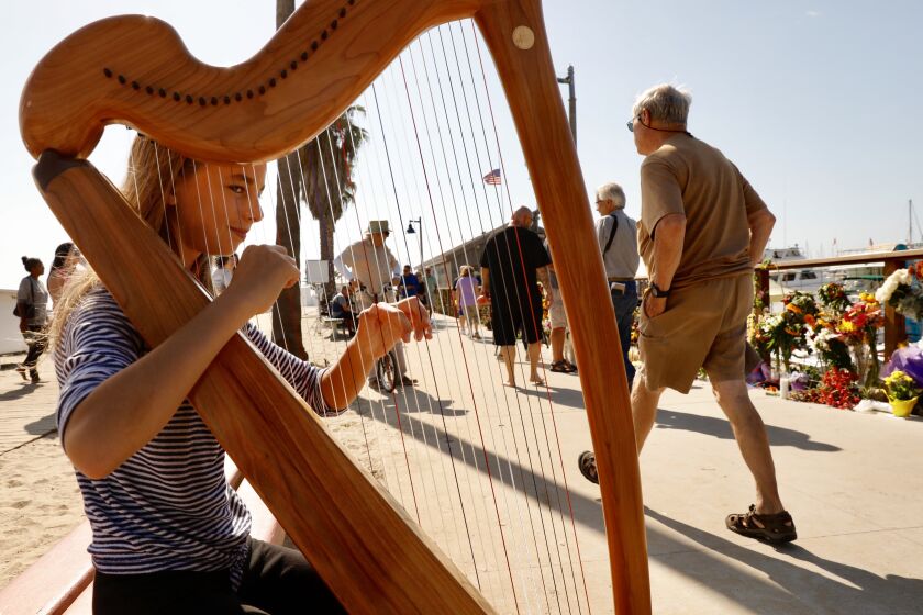 SANTA BARBARA CA SEPTEMBER 4, 2019 -- CJ Andelman, 12, from Santa Barbara, who with her twin sister have recently become scuba divers, plays her harp at the memorial in Santa Barbara Harbor Wednesday morning, September 4, 2019. (Al Seib / Los Angeles Times)