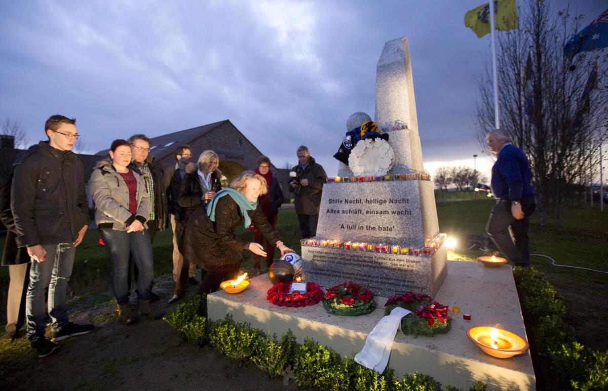 Soccer balls, wreaths and candles are left at the base of the newly inaugurated Christmas Truce monument in Messines, Belgium.