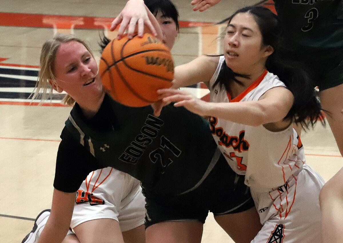 Edison's Taylor Savage (21) and Huntington Beach's Jaylee Kao (33) dive for a loose ball on Saturday.