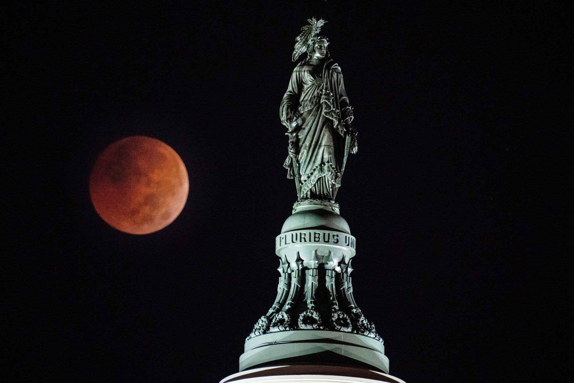 A Beaver Blood Moon Lunar Eclipse is seen behind the Statue of Freedom atop the dome of the U.S. Capitol Building 