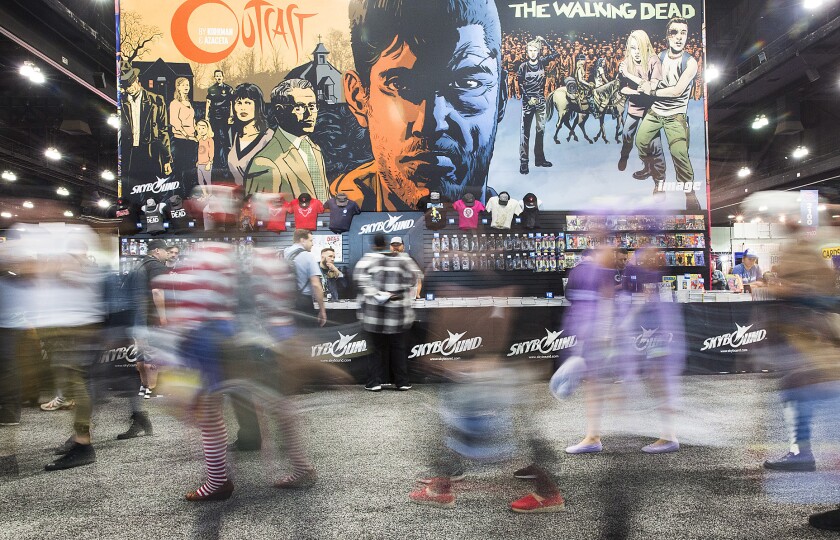 Wondercon attendees walk past "The Walking Dead" booth at WonderCon 2016 at the Los Angeles Convention Center.