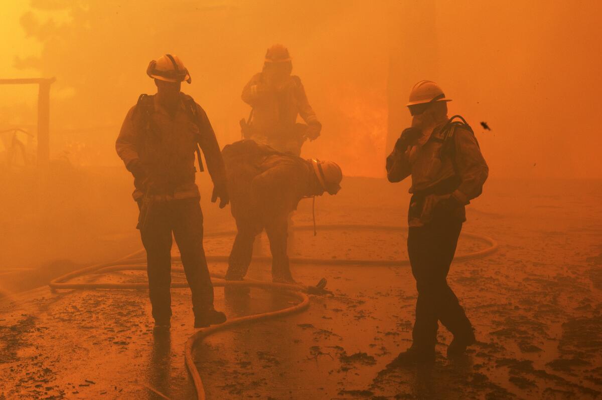 Firefighters cough and bend over amid thick orange smoke.