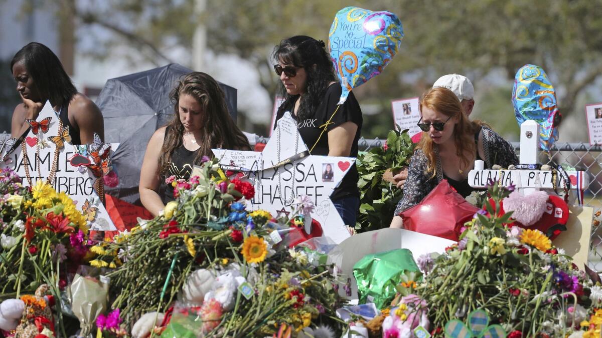 In this Feb. 25, 2018 file photo, mourners bring flowers as they pay tribute at a memorial for the victims of the shooting at Marjory Stoneman Douglas High School, in Parkland, Fla.