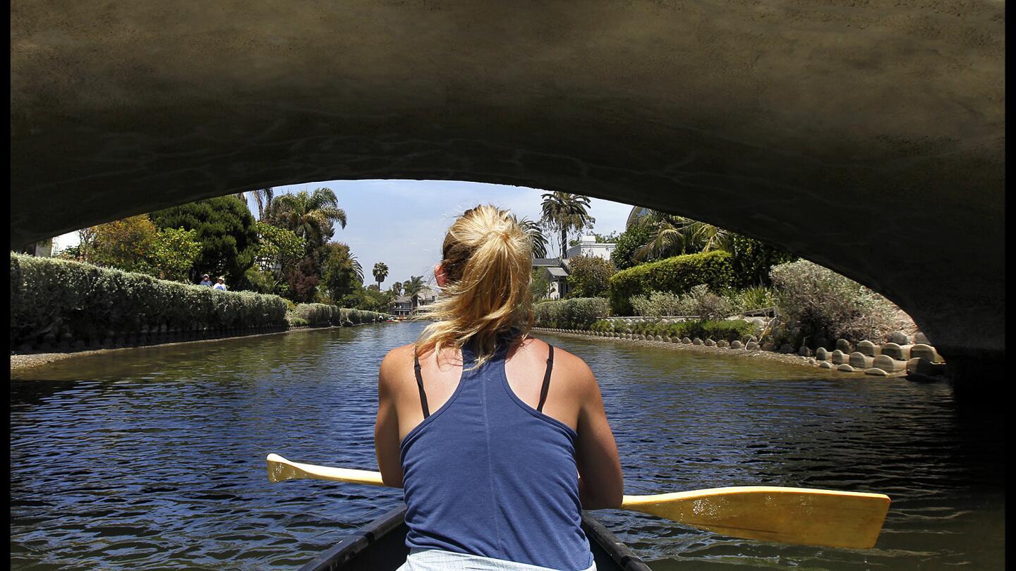 Brigette Edler rows a boat under a bridge at the Venice Canals.