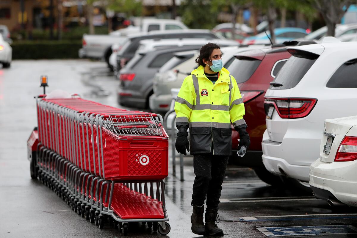 A Target employee collects shopping carts on Tuesday in Costa Mesa. 