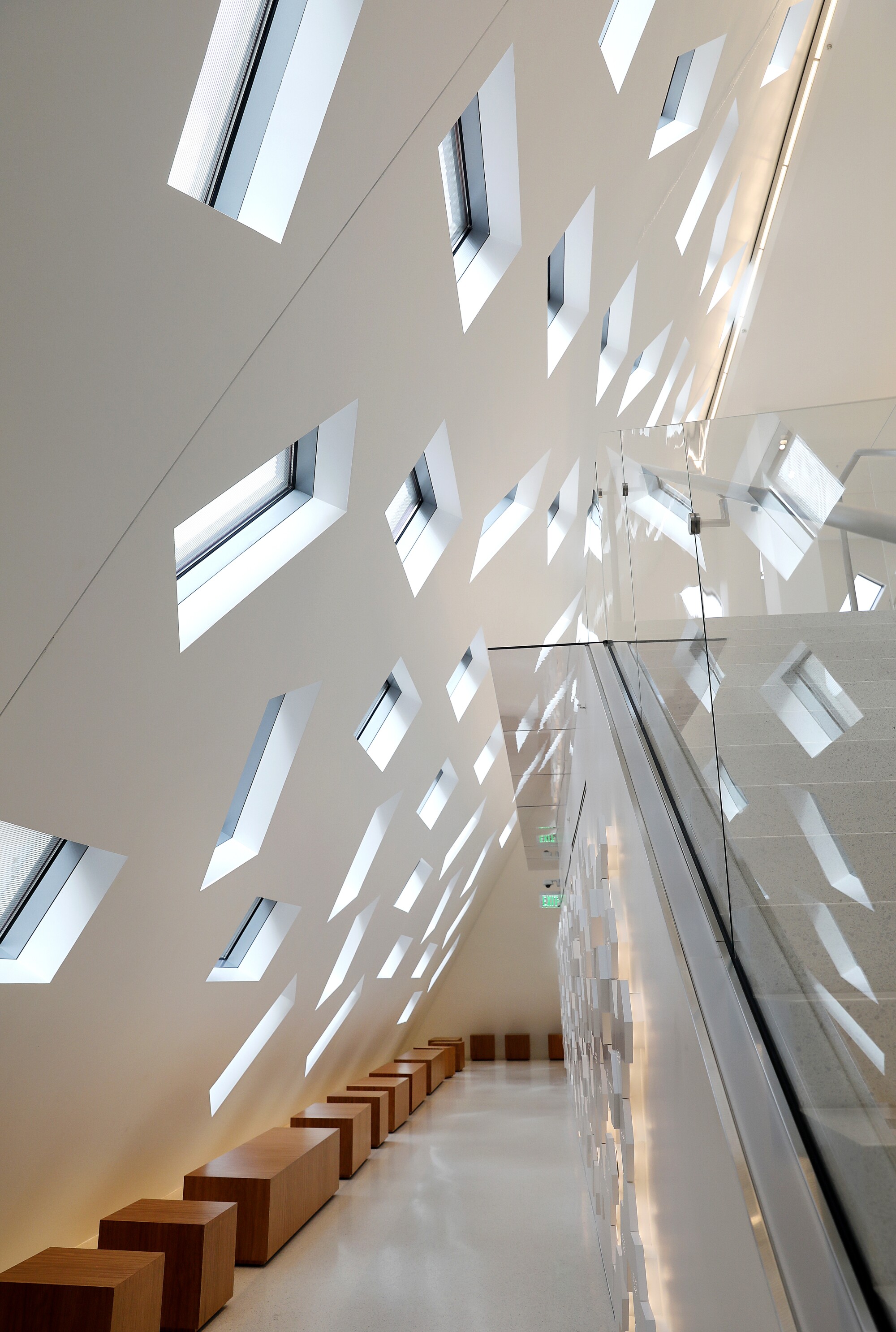 A lobby area features slanted walls punctured by windows at irregular angles
