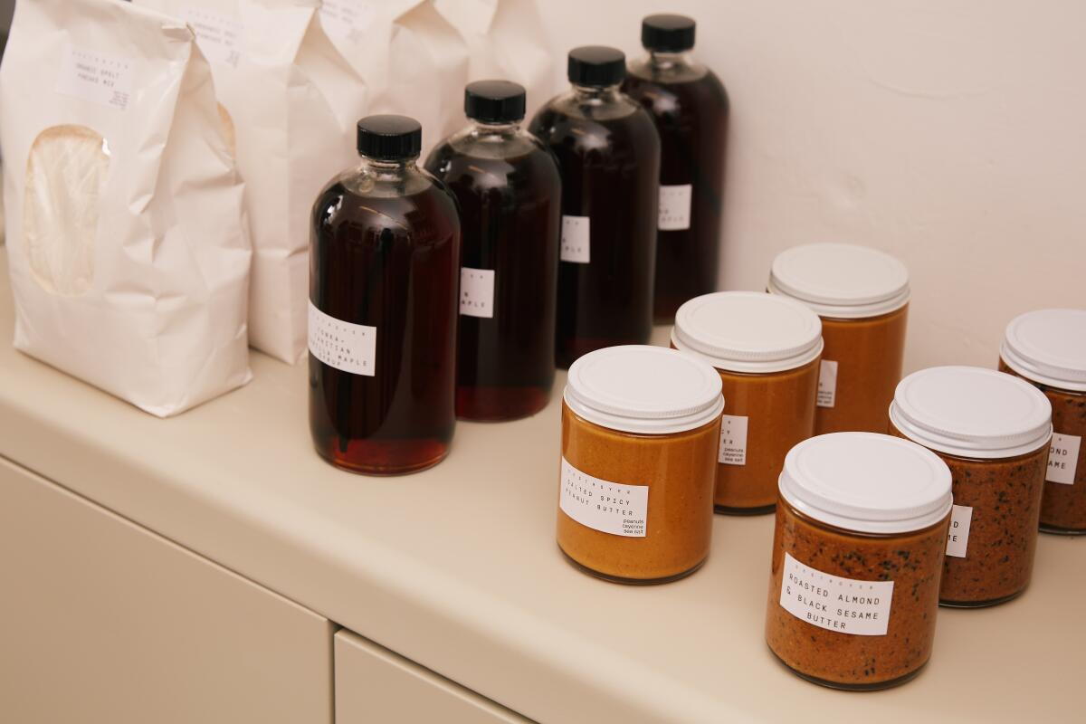 White bags, glass bottles filled with dark liquid and jars with white lids and labels are lined up in neat rows.