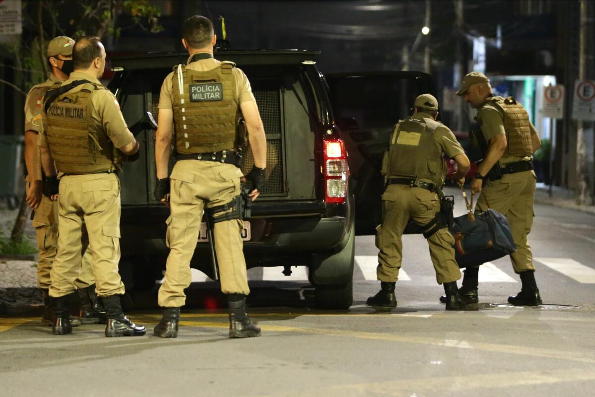 Military police officers carry a bag filled with money left behind by bank robbers in Criciuma, Brazil 