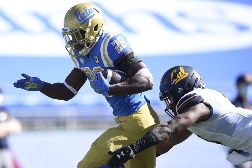 UCLA running back Brittain Brown, left, runs the ball for a touchdown past California safety Elijah Hicks during the second half of an NCAA college football game against California in Los Angeles, Sunday, Nov. 15, 2020. UCLA won 34-10. (AP Photo/Kelvin Kuo)