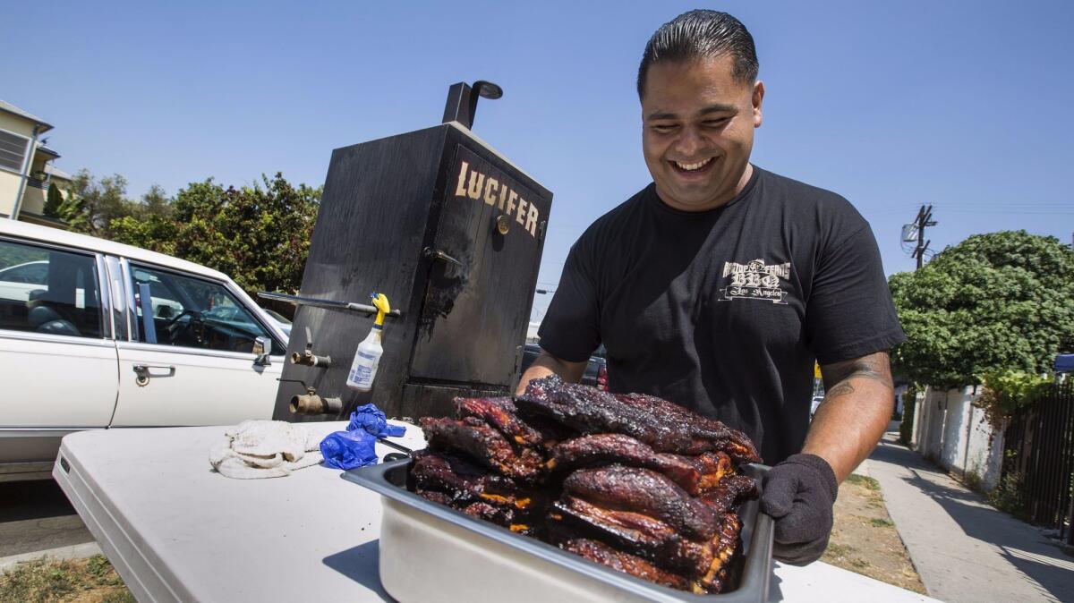 Ragtop Fern's owner/chef Fernando Carrillo sets out ribs and brisket from the smoker in front of his apartment in Los Angeles, Calif.