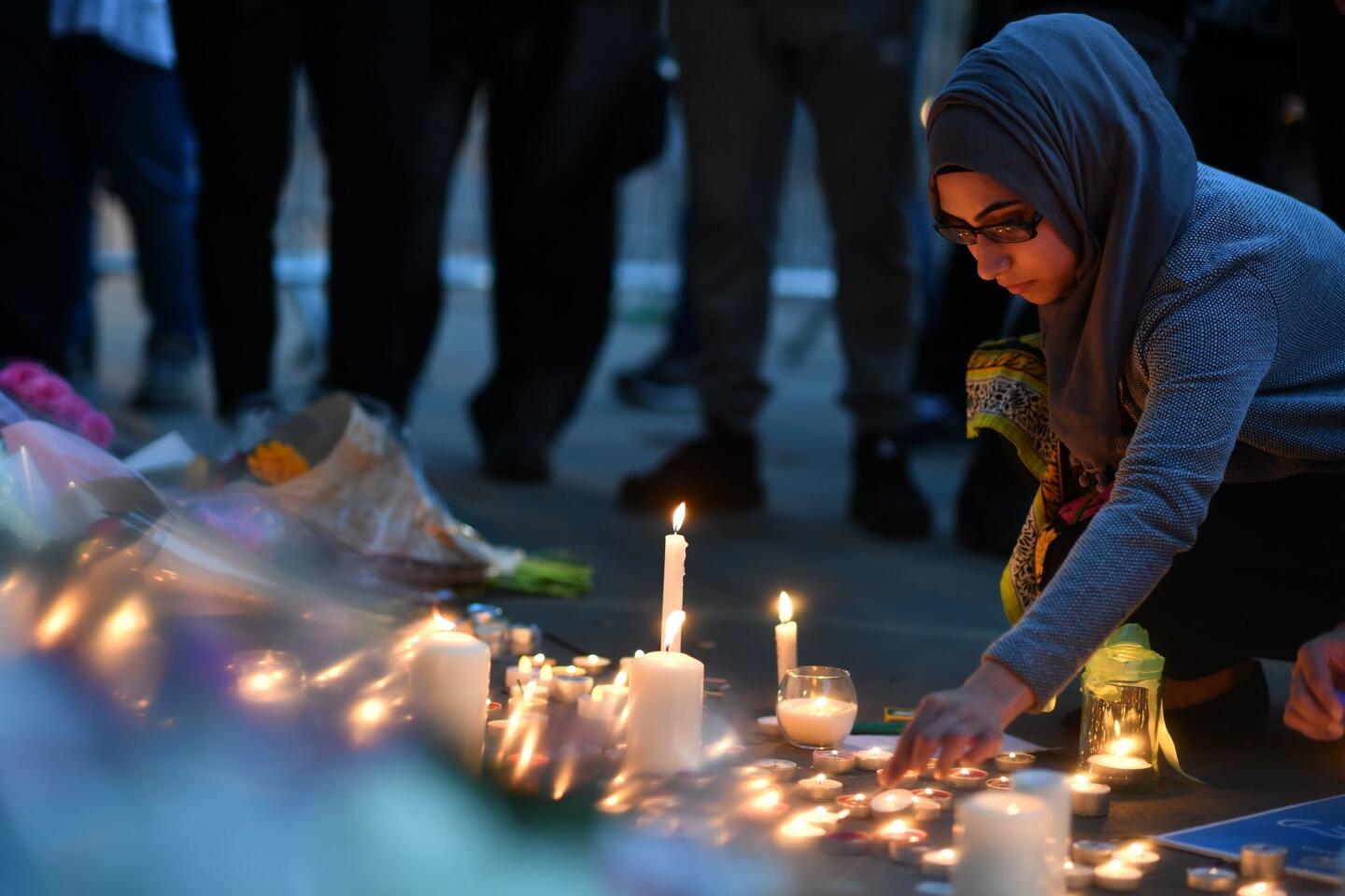 A woman lights candles set up in front of floral tributes in Albert Square on Tuesday.