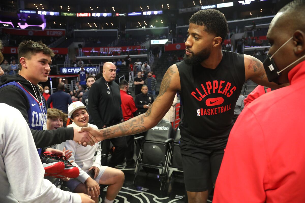 Clippers star Paul George shakes hands with a fan before practicing at Crypto.com Arena.