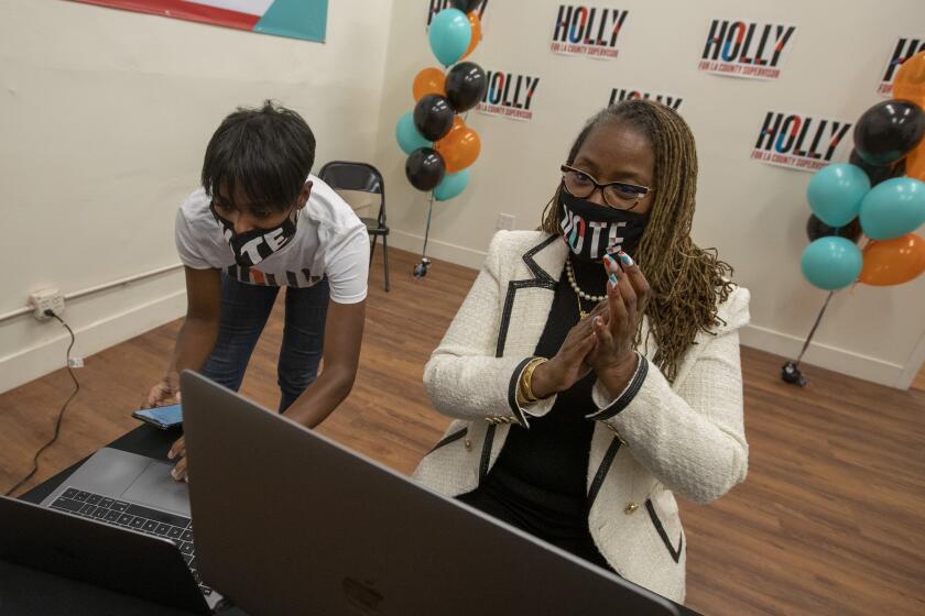 LOS ANGELES, CA - NOVEMBER 03: State Senator Holly Mitchell, right, and campaign manager Lenee Richards, left, watch as election results come in showing her ahead in her race against Herb Wesson for a seat on the L.A. County Board of Supervisors at her campaign headquarters on Tuesday, Nov. 3, 2020 in Los Angeles, CA. (Brian van der Brug / Los Angeles Times)