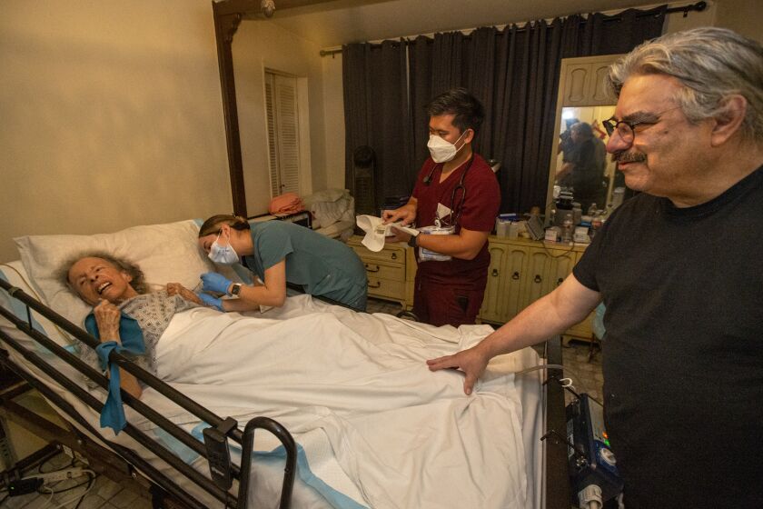 LOS ANGELES, CA-OCTOBER 7, 2022: Licensed Vocational Nurse Angela Tapia administers a dose of the Moderna COVID-19 booster vaccine to Maria Salazar, 88, at her home in Los Angeles as her son Louis Salazar Jr. 64, right, and Public Health Nurse Bryan Phan observe. Louis and his father Louis Sr. 90, were earlier given the booster shot by Tapia. The Los Angeles County Department of Public Health runs a program that provide COVID vaccines to people who are homebound. (Mel Melcon / Los Angeles Times)