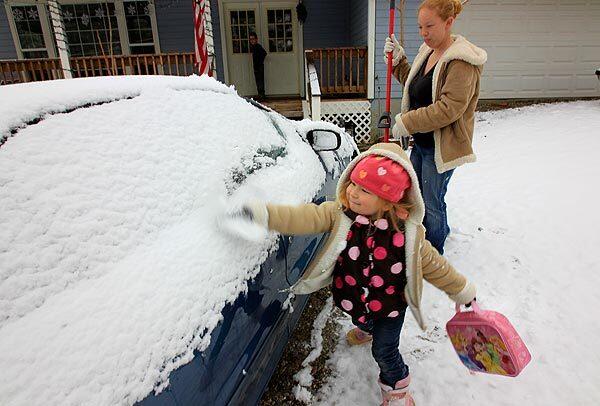 Four-year-old Caelee Kelly helps her mother, Tiffany, clean snow off their car in Frazier Park in Kern County.