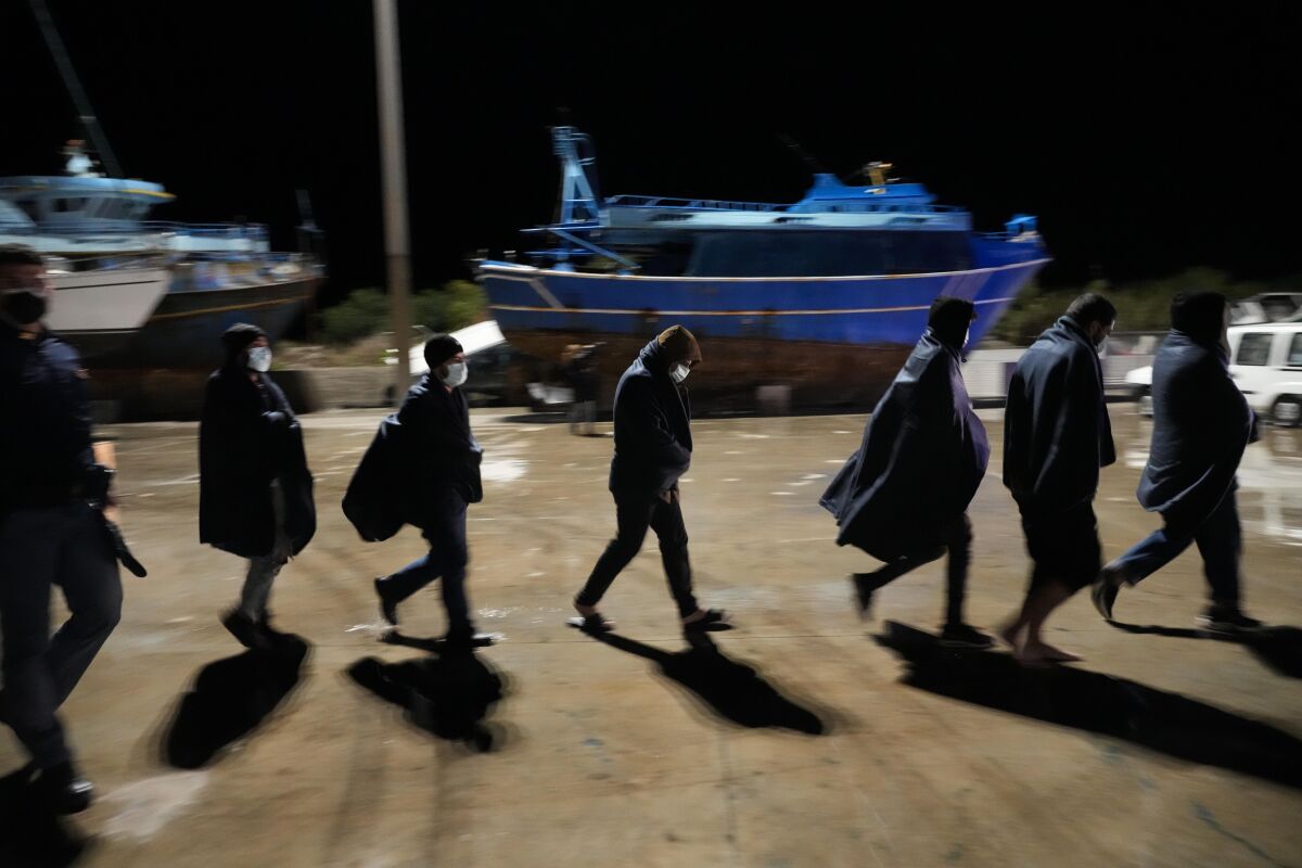 Migrants walk on the quay after disembarking in Roccella Jonica, Calabria region, southern Italy, early Sunday, Nov. 14, 2021. The Italian Coast Guard rescued over three hundred young men and boys, mostly from Egypt, in heavy storms as their fishing boat floundered off the coast of Calabria Saturday night. In an operation that finished at dawn Sunday morning, the Coast Guard rescue team from Roccella Jonica made three trips out to the fishing boat where they transferred groups of migrants to their rescue boat and brought them to port barefoot, soaking wet, and shivering. (AP Photo/Alessandra Tarantino)