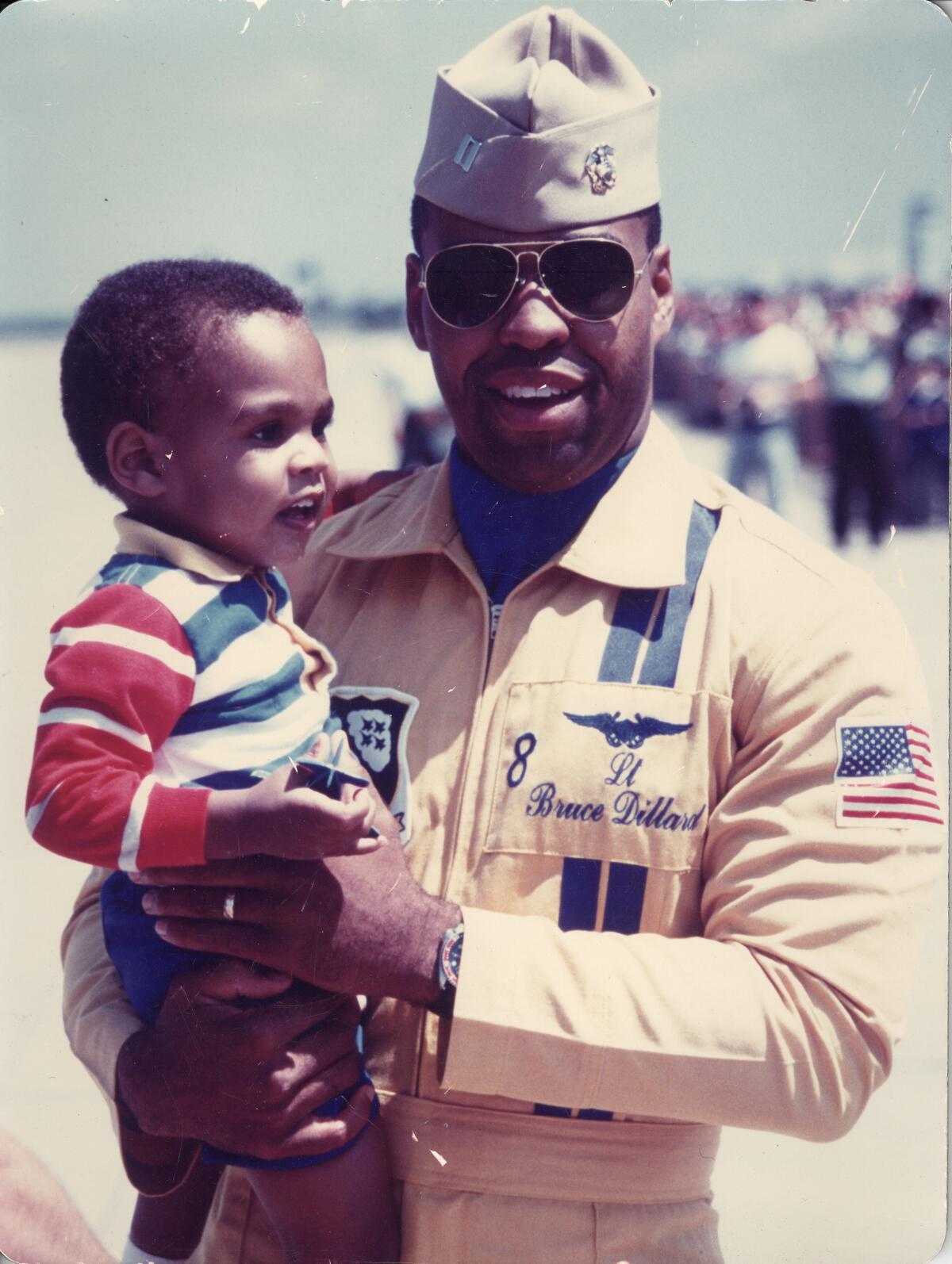 A naval aviator in uniform holding his young son