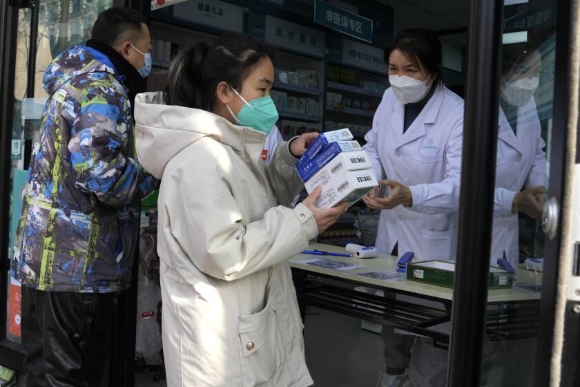 A resident carries away medicine bought at a pharmacy in Beijing, Friday, Dec. 9, 2022. China began implementing a more relaxed version of its strict "zero COVID" policy on Thursday amid steps to restore normal life, but also trepidation over a possible broader outbreak once controls are eased. (AP Photo/Ng Han Guan)